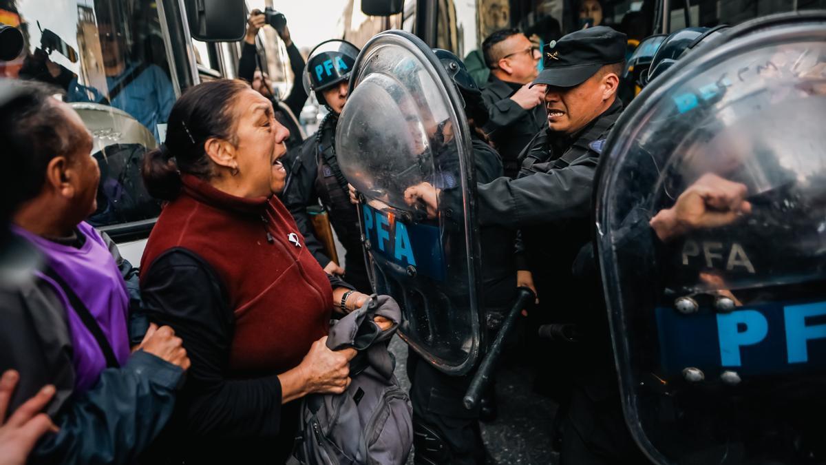 Miembros de la Policía Federal Argentina (PFA) se enfrentan con una mujer durante una manifestación de jubilados