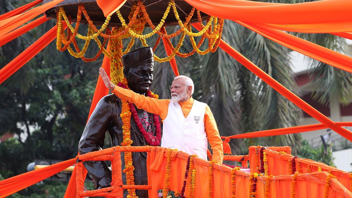 El primer ministro indio, Narendra Modi, saluda a sus simpatizantes junto a la estatua del educador y reformista Madan Mohan Malviya, durante un acto de su gira electoral. EFE/HARISH TYAGI